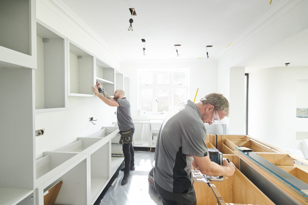 Two Contractors Working on Cabinets in a Kitchen