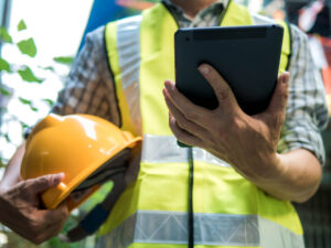 Engineering man standing with yellow safety helmet and holding tablet, work concept