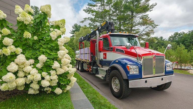 L&W Supply truck parked next to hydrangea bush with white flowers.